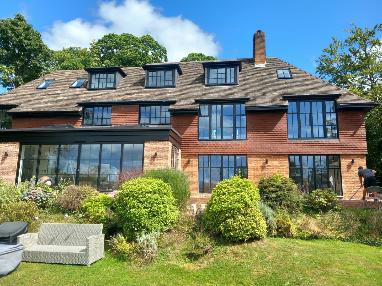 A large red-brick home with black steel windows and steel framed doors, combining modern design with timeless style.
