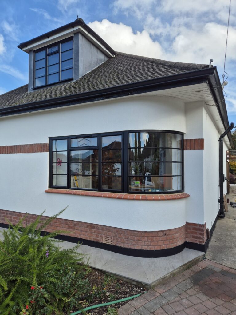 A striking black-framed curved bay window with art deco windows that add timeless elegance to the house’s exterior design.