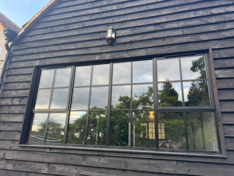A set of black-framed heritage windows with a period finish, featuring large glass panes and a steel metal window design.